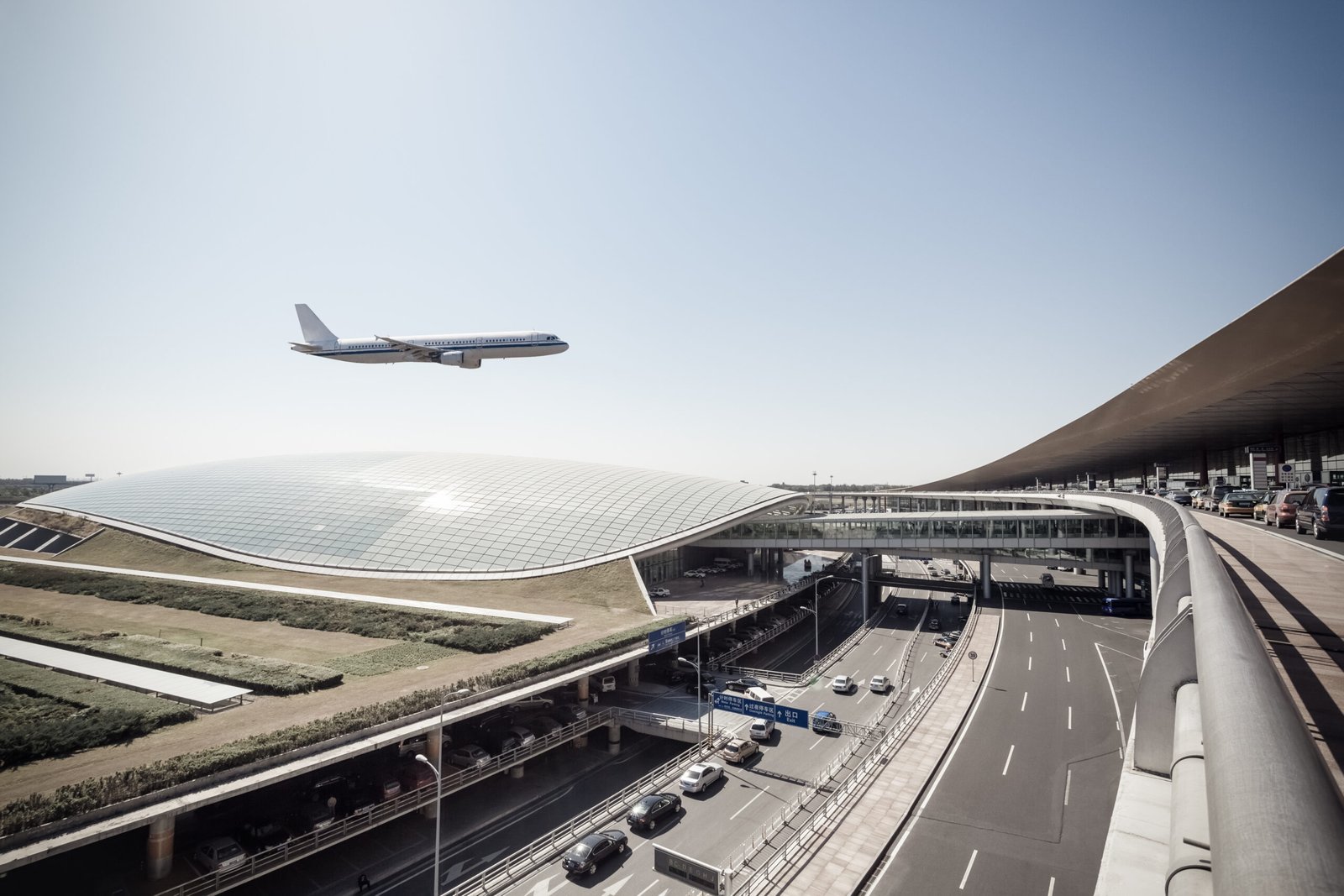Aircraft over terminal at Beijing Daxing International Airport with elevated roads