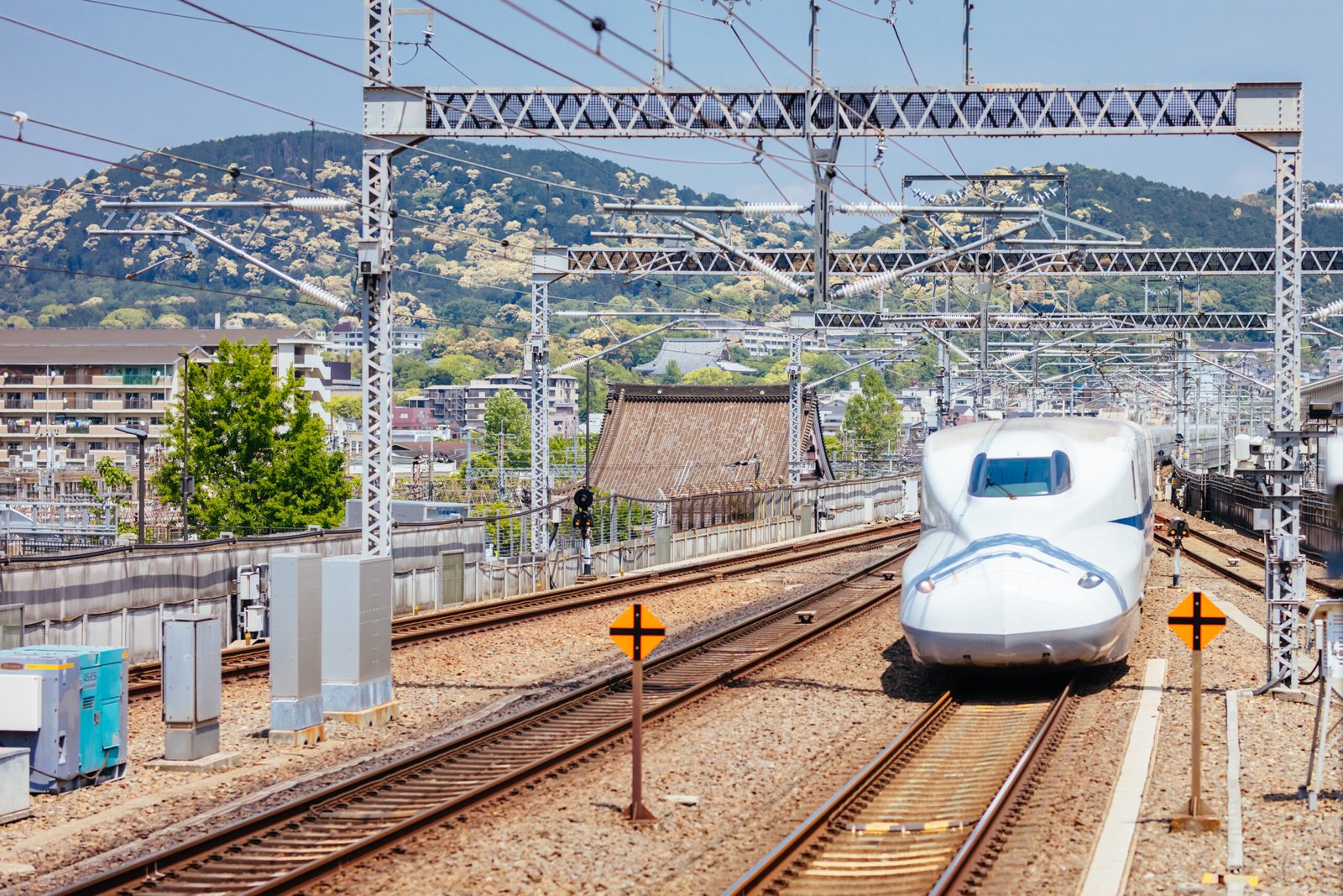 High-speed train passing through an urban station with catenary and concrete track