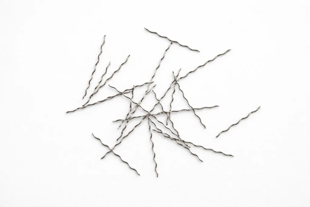Twisted steel fiber scattered on a light gray background for reinforced concrete applications