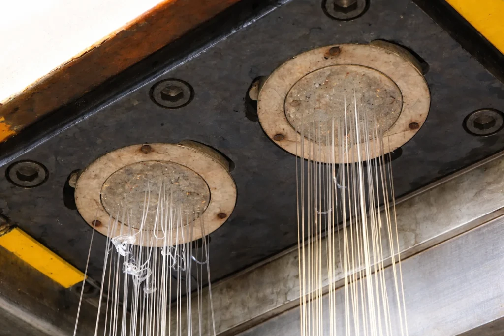 Molten polypropylene being extruded through spinneret holes and cooled into filaments