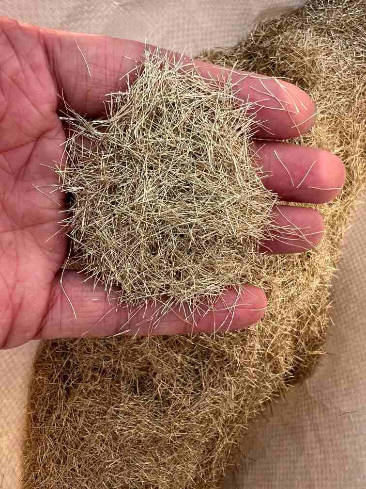 hand holding loose brass-coated micro steel fiber for UHPC reinforcement